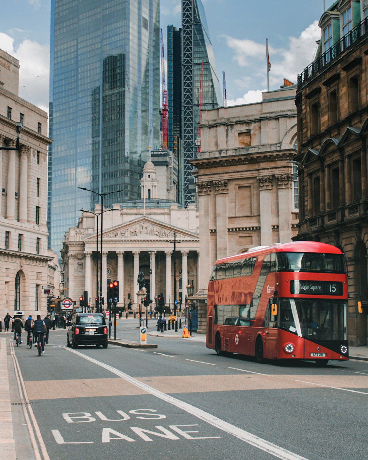 A red London bus passing the Royal Exchange, with BUS LANE painted in large letters on the road